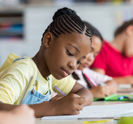 Pupil writing at desk in classroom at the elementary school